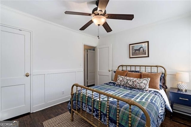 bedroom with dark wood-type flooring, a wainscoted wall, ornamental molding, and ceiling fan