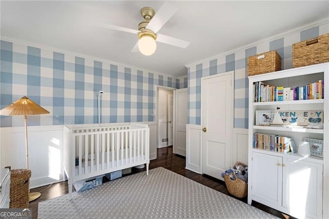 bedroom featuring a wainscoted wall, wood finished floors, and wallpapered walls