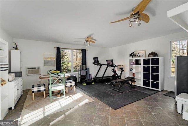 exercise room featuring a wall unit AC and a ceiling fan