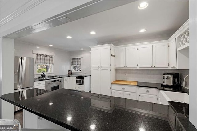 kitchen with white cabinetry, appliances with stainless steel finishes, backsplash, and recessed lighting