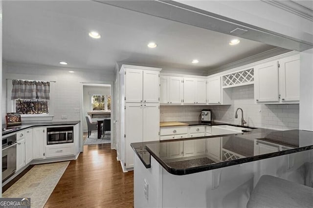 kitchen featuring dark wood-style floors, stainless steel appliances, a sink, and white cabinetry