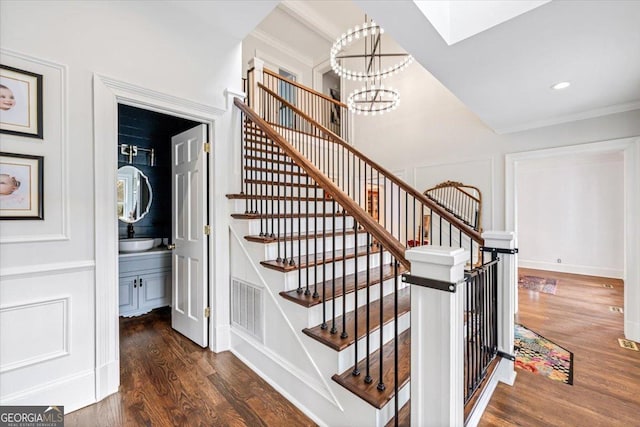 stairway featuring a notable chandelier, recessed lighting, a decorative wall, wood finished floors, and visible vents