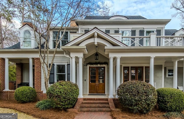 property entrance featuring french doors, brick siding, and a balcony