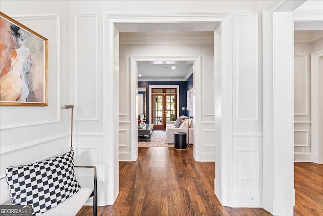 hallway with crown molding, a decorative wall, dark wood-type flooring, and french doors