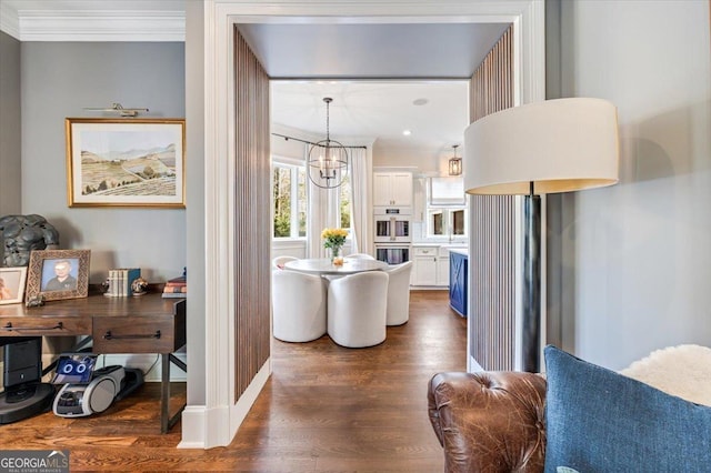 interior space featuring pendant lighting, dark wood-type flooring, ornamental molding, open floor plan, and white cabinets