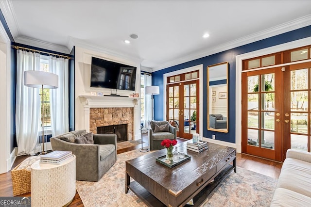 living area featuring crown molding, a fireplace, wood finished floors, and french doors