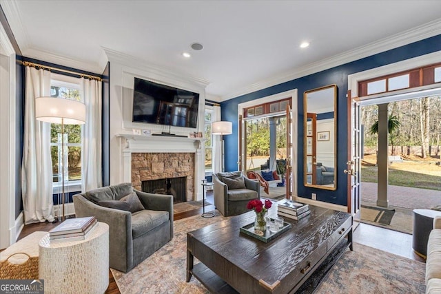 living area featuring crown molding, a stone fireplace, recessed lighting, and a healthy amount of sunlight