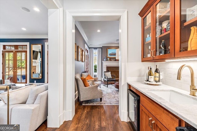 bar featuring a sink, dark wood-style floors, ornamental molding, backsplash, and dishwasher