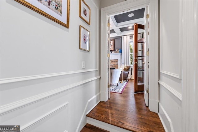 hall with coffered ceiling, beamed ceiling, and wood finished floors