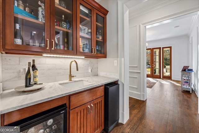 bar featuring dark wood-style floors, backsplash, a sink, and crown molding