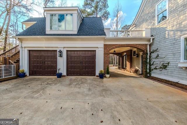 view of side of home with a garage, concrete driveway, brick siding, and a shingled roof