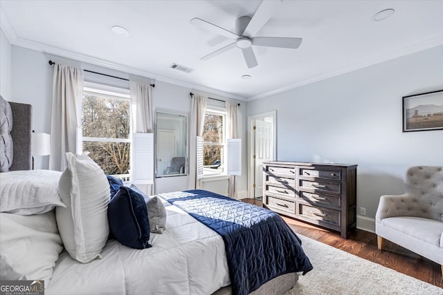 bedroom with ornamental molding, wood finished floors, visible vents, and baseboards