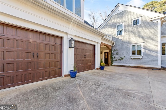 view of property exterior with an attached garage, concrete driveway, and brick siding