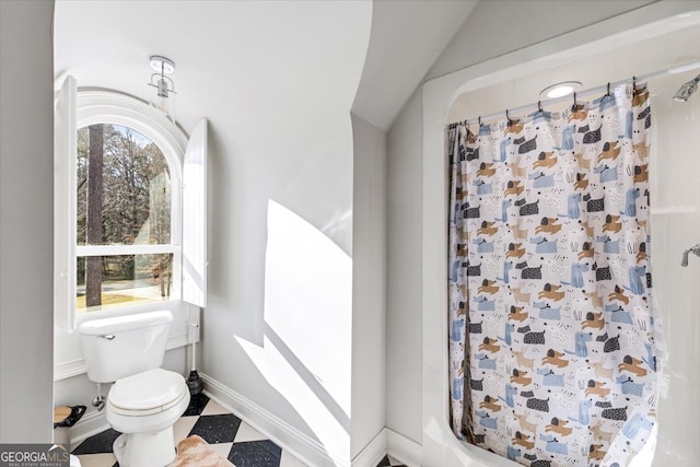 bathroom with toilet, a shower with curtain, baseboards, and tile patterned floors