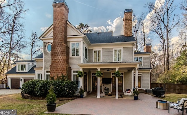 back of property with a chimney, a ceiling fan, fence, a garage, and driveway