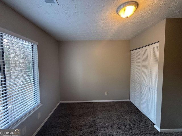 unfurnished bedroom featuring multiple windows, a closet, carpet, and baseboards