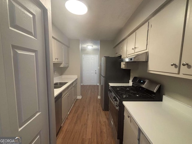 kitchen with under cabinet range hood, dark wood finished floors, stainless steel appliances, and light countertops