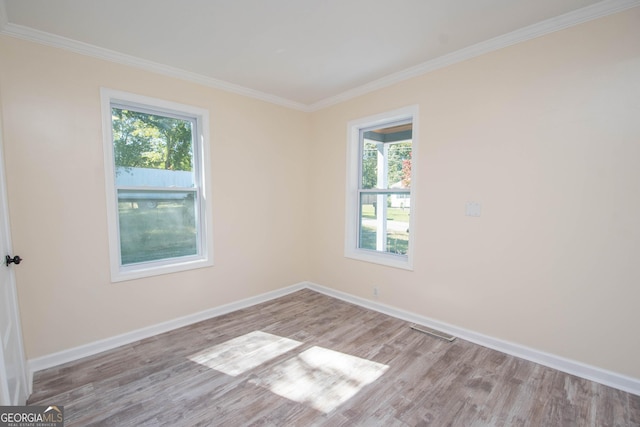 empty room featuring baseboards, visible vents, and crown molding