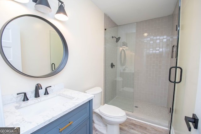 full bathroom with a stall shower, vanity, toilet, and wood finished floors