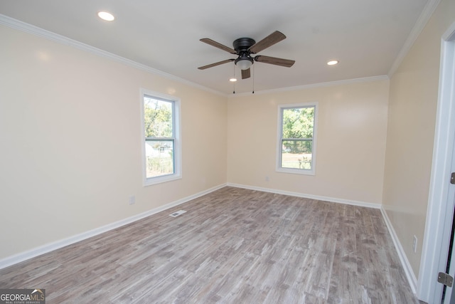 spare room with ornamental molding, visible vents, baseboards, and wood finished floors