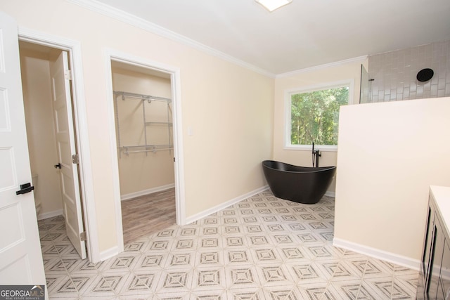 interior space featuring baseboards, ornamental molding, a spacious closet, walk in shower, and a freestanding tub