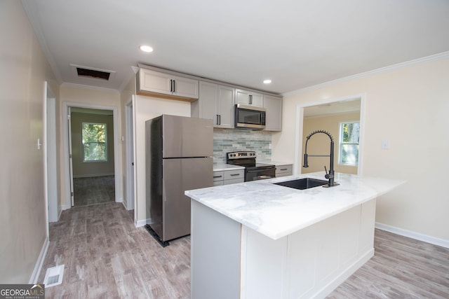 kitchen with a sink, visible vents, ornamental molding, appliances with stainless steel finishes, and backsplash