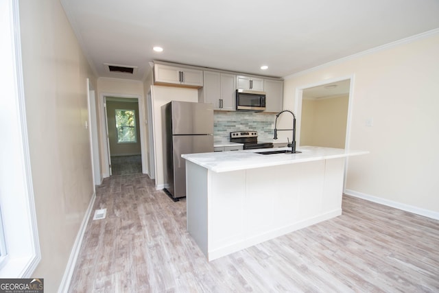 kitchen with light wood-style flooring, a sink, light countertops, appliances with stainless steel finishes, and tasteful backsplash