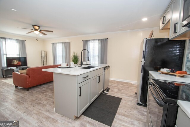 kitchen with stainless steel appliances, a healthy amount of sunlight, a sink, and ornamental molding