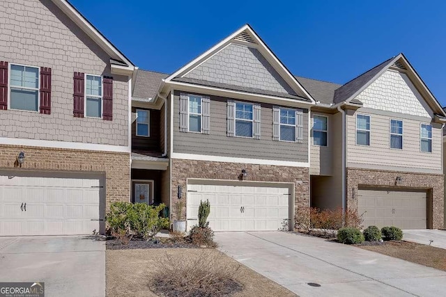 townhome / multi-family property with stone siding, concrete driveway, and an attached garage