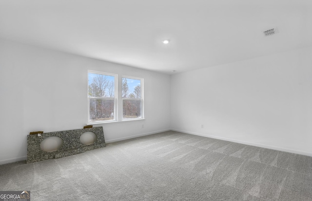 unfurnished room with carpet, visible vents, and baseboards