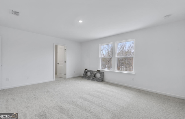 empty room with carpet, visible vents, and baseboards