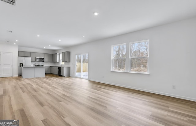 unfurnished living room with light wood finished floors, visible vents, baseboards, and recessed lighting