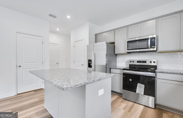 kitchen featuring appliances with stainless steel finishes, light wood-type flooring, gray cabinets, and backsplash