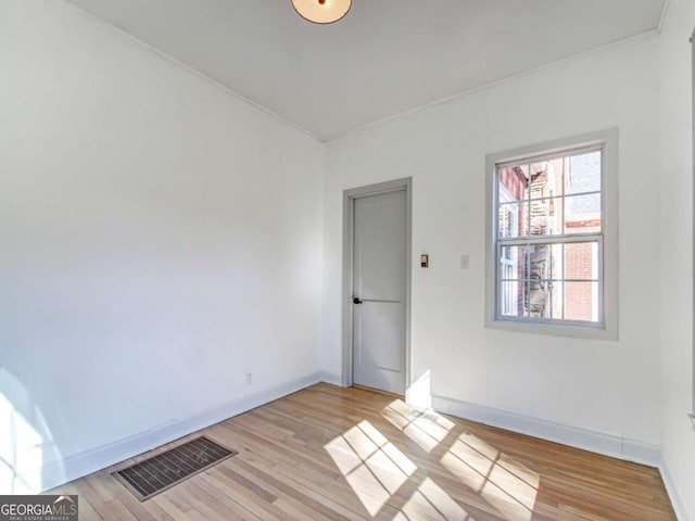 unfurnished room featuring light wood-style floors, visible vents, and baseboards