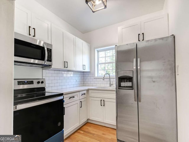 kitchen with stainless steel appliances, tasteful backsplash, a sink, and white cabinets