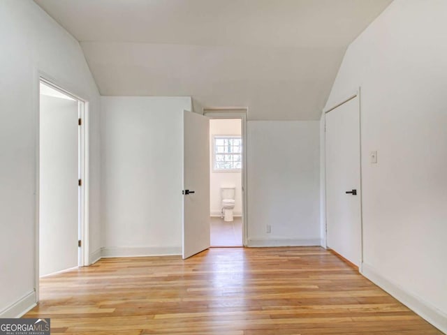 spare room featuring light wood-style floors and vaulted ceiling