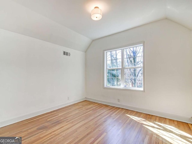 additional living space with lofted ceiling, wood finished floors, visible vents, and baseboards