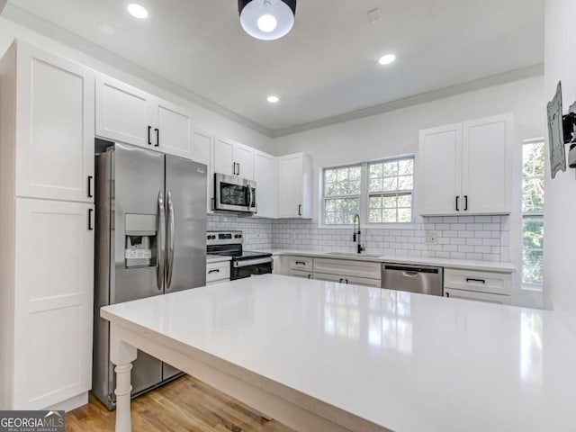 kitchen with appliances with stainless steel finishes, decorative backsplash, a sink, and ornamental molding