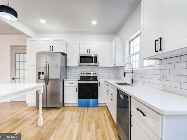 kitchen featuring ornamental molding, stainless steel appliances, a sink, and light countertops