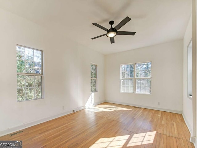 unfurnished room with a healthy amount of sunlight, baseboards, visible vents, and hardwood / wood-style floors