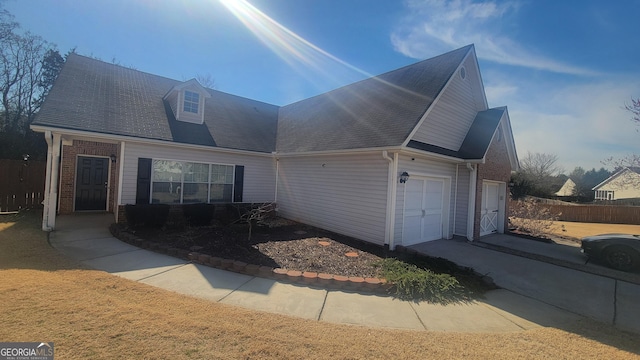 view of front of house featuring a garage, brick siding, and fence