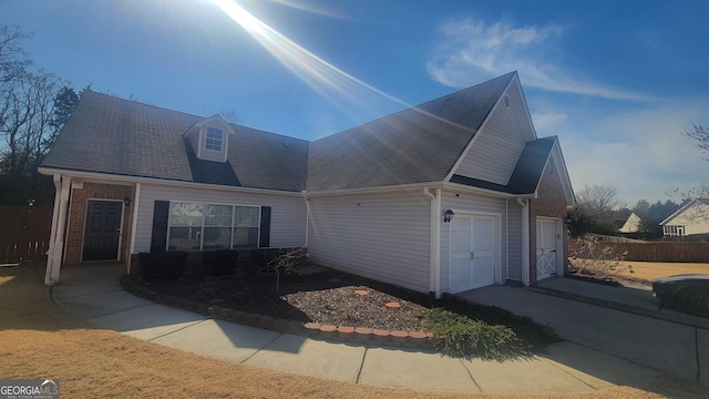 view of front of home with a garage, brick siding, and fence