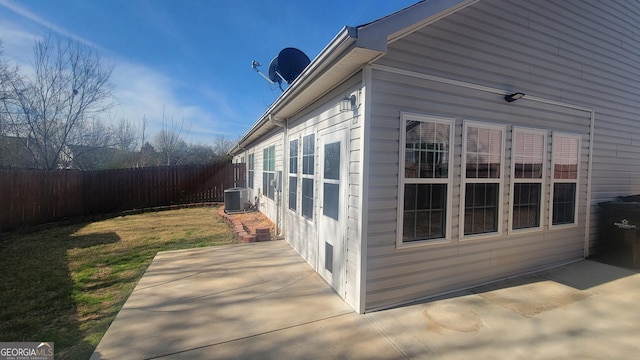 view of side of property with a patio area, fence, cooling unit, and a yard