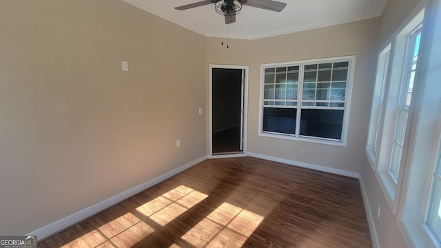 empty room featuring crown molding, wood finished floors, and baseboards