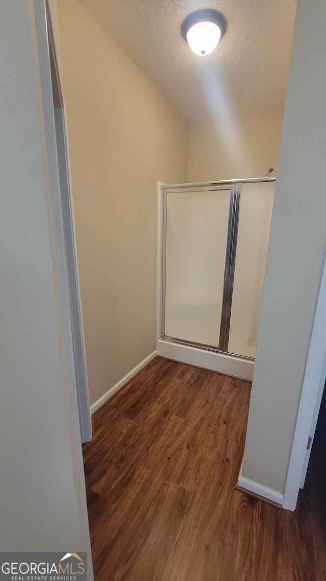 interior space with a textured ceiling, wood finished floors, and baseboards