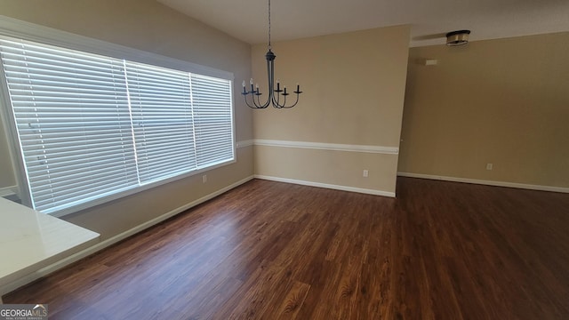 unfurnished dining area featuring an inviting chandelier, baseboards, and wood finished floors