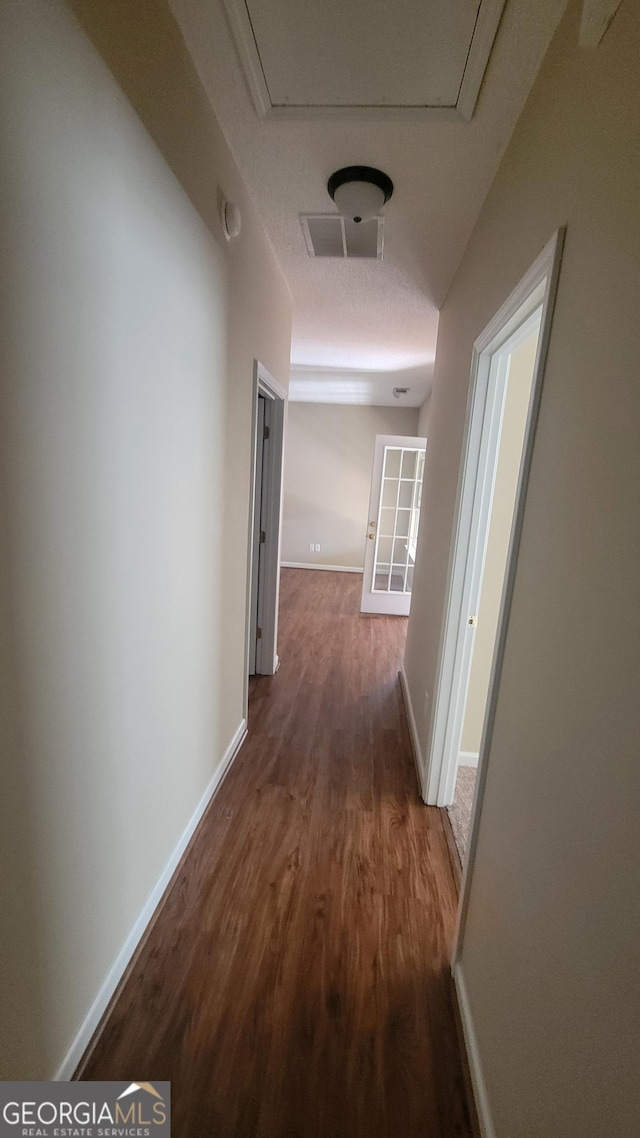 hall featuring baseboards, visible vents, and wood finished floors