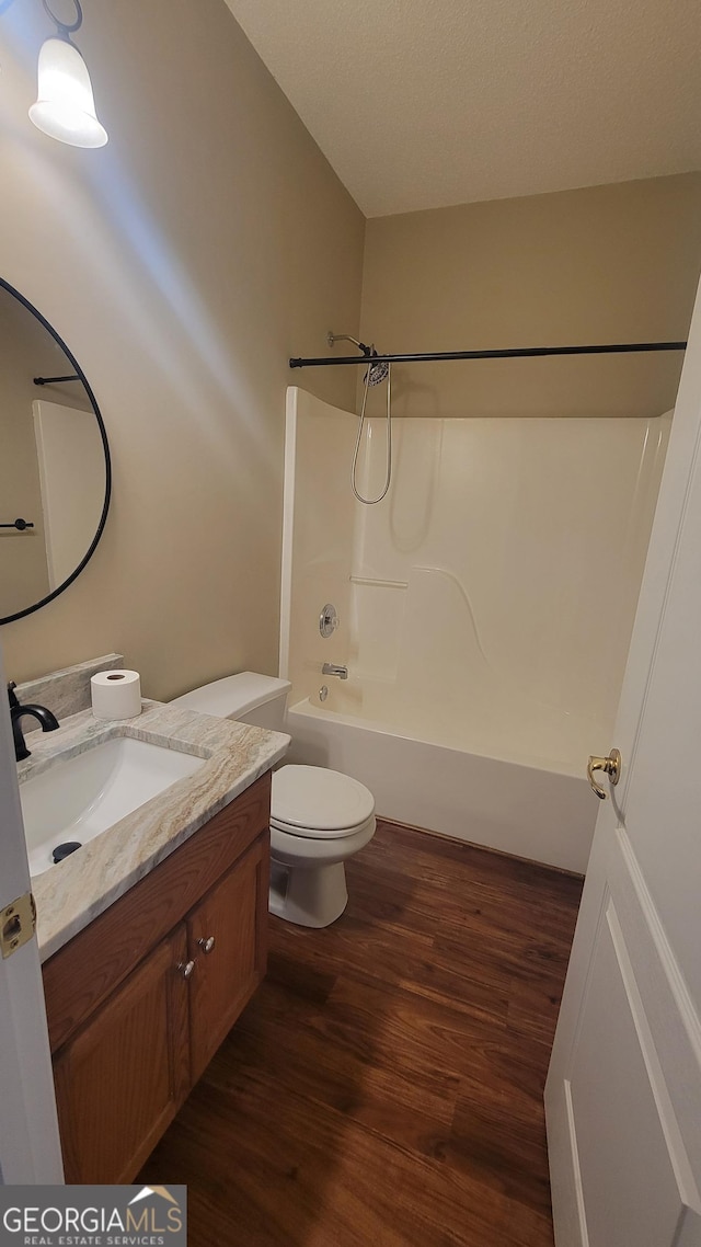 bathroom featuring  shower combination, toilet, wood finished floors, and vanity