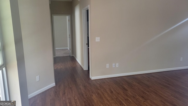 spare room featuring dark wood-style flooring and baseboards