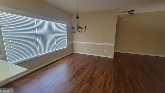 unfurnished dining area featuring a chandelier, baseboards, and wood finished floors